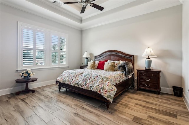 bedroom with crown molding, ceiling fan, a tray ceiling, and light hardwood / wood-style flooring