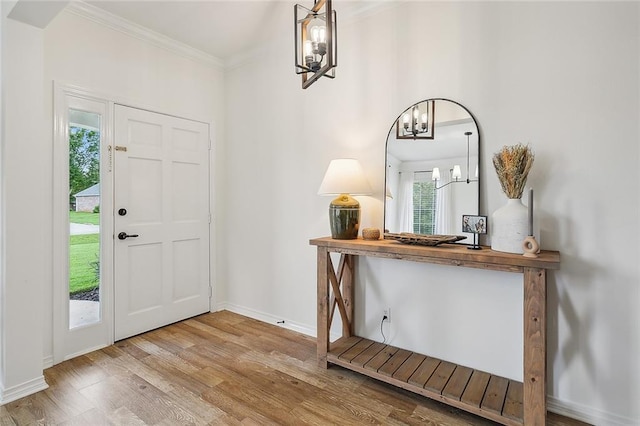 entrance foyer with ornamental molding, a chandelier, and light hardwood / wood-style floors