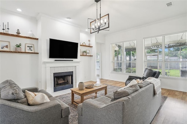 living room with ornamental molding, a healthy amount of sunlight, a fireplace, and light wood-type flooring