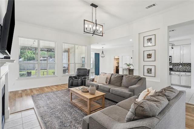 living room featuring ornamental molding, a chandelier, and light hardwood / wood-style floors