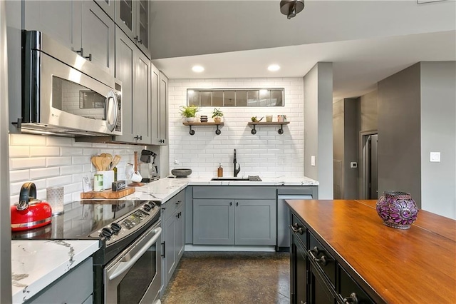 kitchen with appliances with stainless steel finishes, sink, decorative backsplash, and butcher block countertops