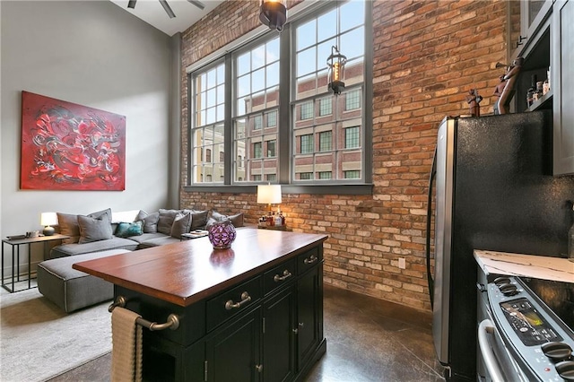 kitchen with vaulted ceiling, stainless steel appliances, and brick wall