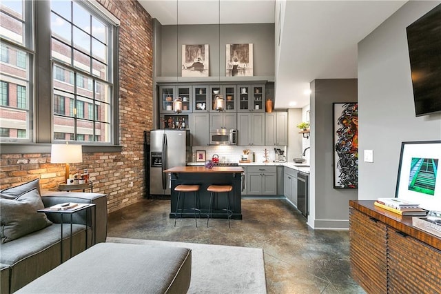 kitchen with pendant lighting, brick wall, appliances with stainless steel finishes, and gray cabinets