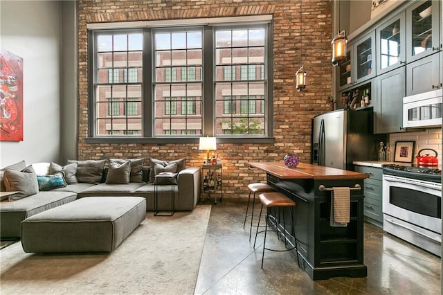 kitchen featuring plenty of natural light, stainless steel appliances, and brick wall