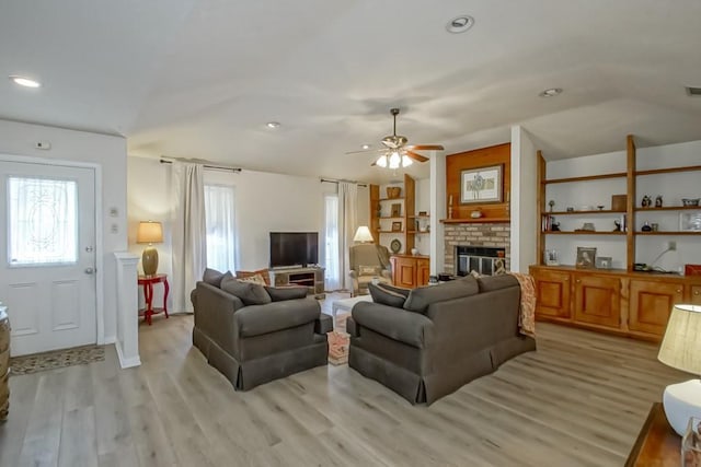 living room featuring a fireplace, lofted ceiling, a wealth of natural light, and light wood-type flooring