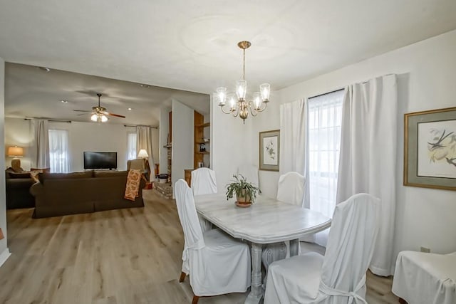 dining space featuring ceiling fan with notable chandelier and light hardwood / wood-style floors