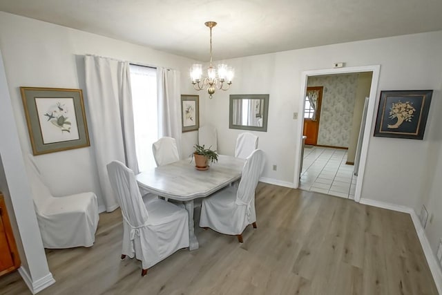 dining room featuring a healthy amount of sunlight, a chandelier, and light hardwood / wood-style flooring