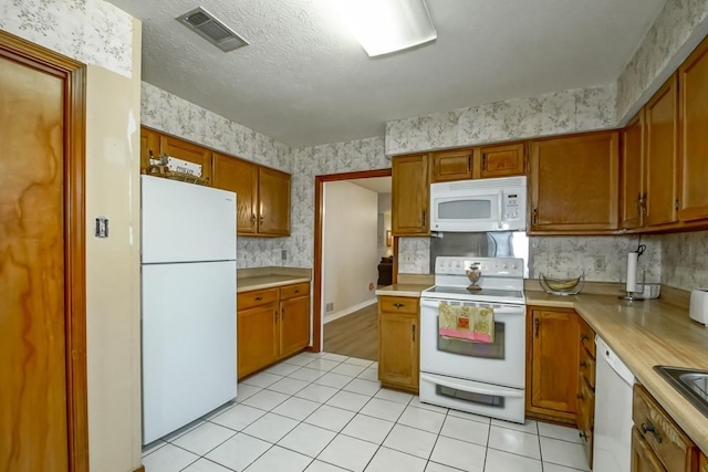 kitchen with light tile patterned floors, a textured ceiling, and white appliances