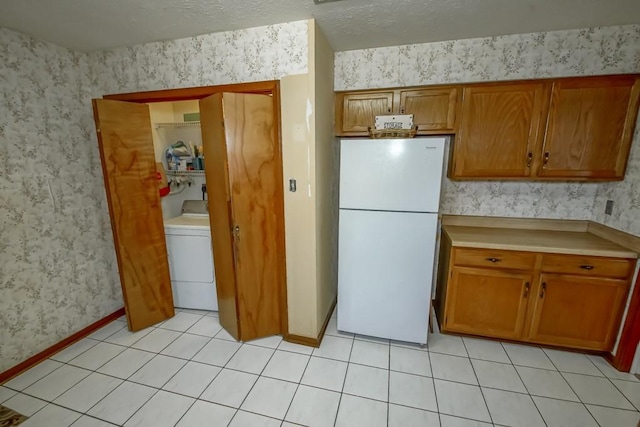 kitchen featuring light tile patterned floors, washer / dryer, a textured ceiling, and white refrigerator