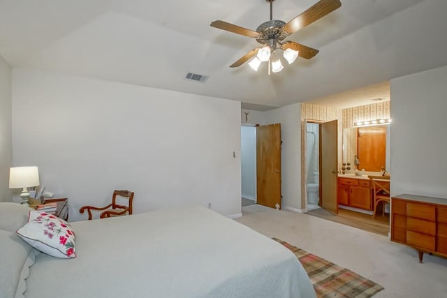 bedroom featuring light colored carpet, ceiling fan, and ensuite bathroom