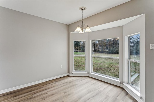 unfurnished dining area with a chandelier and light hardwood / wood-style floors