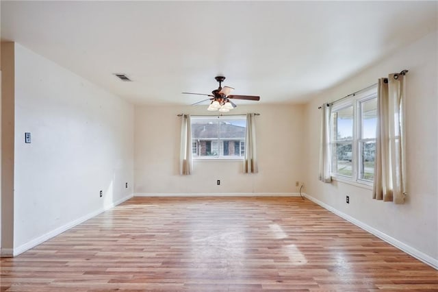 empty room featuring plenty of natural light, ceiling fan, and light wood-type flooring