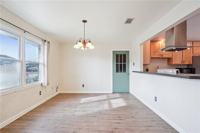 kitchen with hanging light fixtures, island range hood, a chandelier, and light hardwood / wood-style flooring