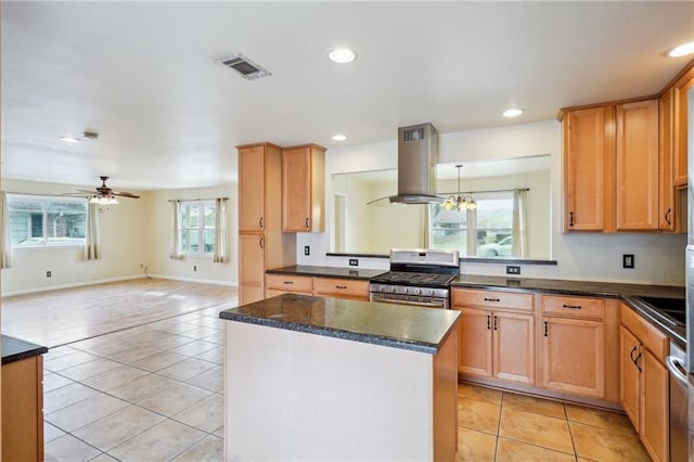 kitchen featuring stainless steel gas range oven, light tile patterned floors, a kitchen island, island exhaust hood, and ceiling fan with notable chandelier