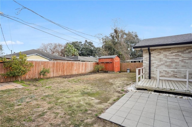 view of yard with a wooden deck, a patio area, and a storage unit