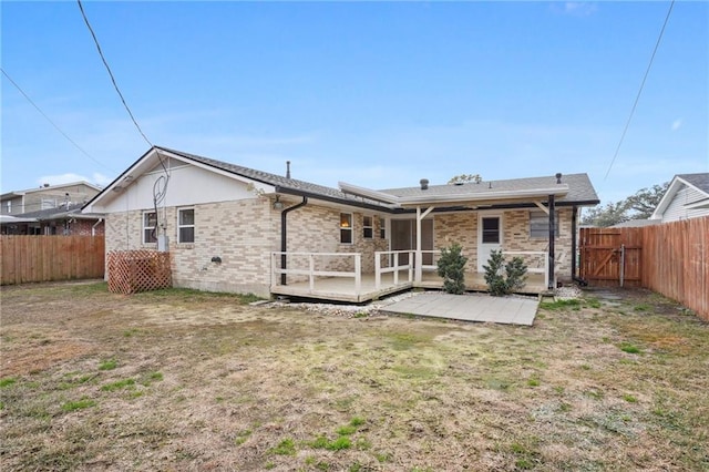 back of house with a deck and a lawn