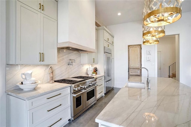 kitchen with sink, hanging light fixtures, high end appliances, custom exhaust hood, and light stone countertops