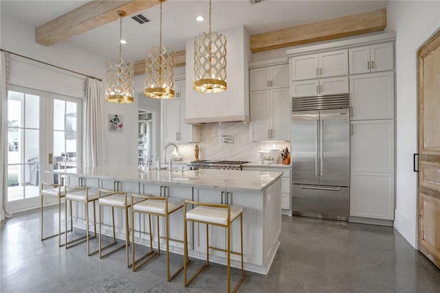 kitchen with sink, a kitchen breakfast bar, hanging light fixtures, stainless steel built in fridge, and a center island with sink