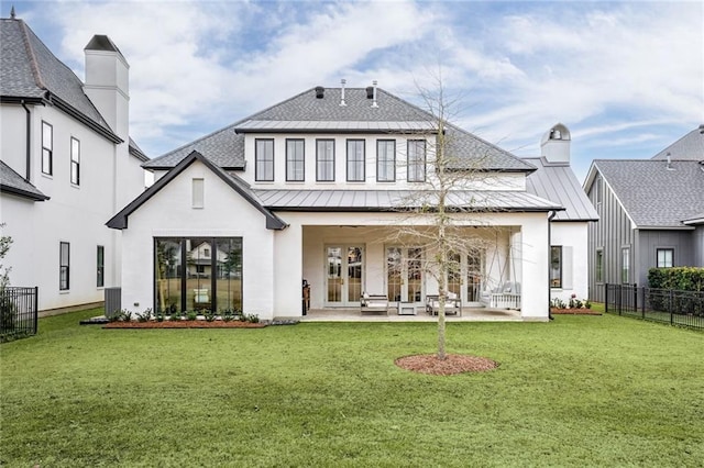 back of property with french doors, a patio, and a lawn