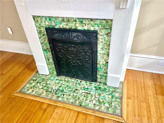 details featuring hardwood / wood-style flooring and a tiled fireplace