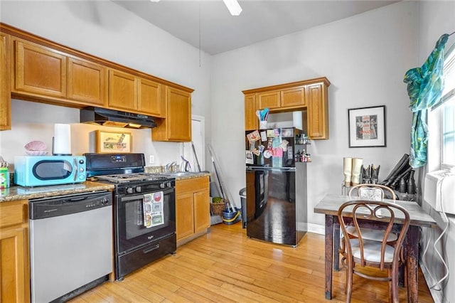 kitchen with ceiling fan, light stone countertops, light wood-type flooring, and black appliances