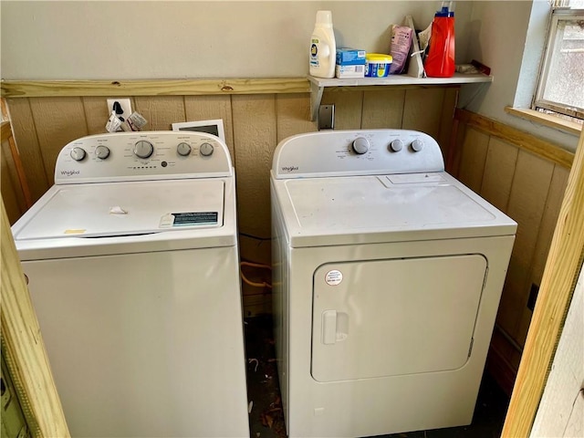 washroom with washing machine and clothes dryer and wood walls