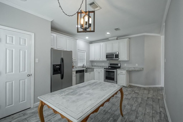 kitchen featuring appliances with stainless steel finishes, decorative light fixtures, and white cabinets