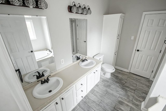 bathroom with vanity, a tub, and toilet