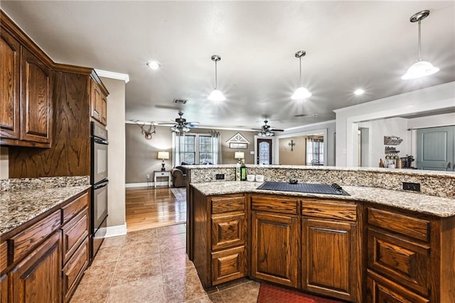 kitchen with hanging light fixtures, light stone countertops, light tile patterned floors, and black appliances