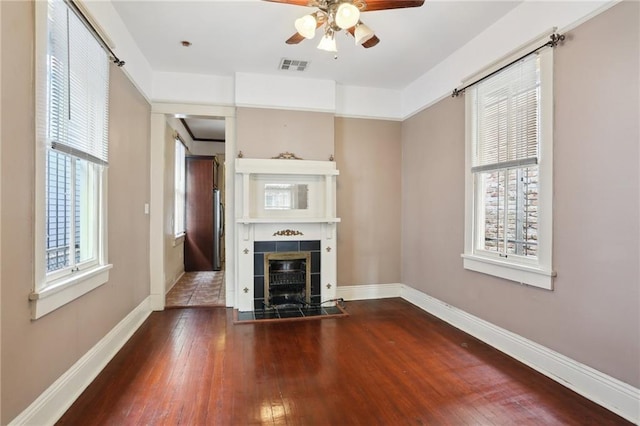 unfurnished living room with hardwood / wood-style flooring, ceiling fan, a tile fireplace, and a wealth of natural light