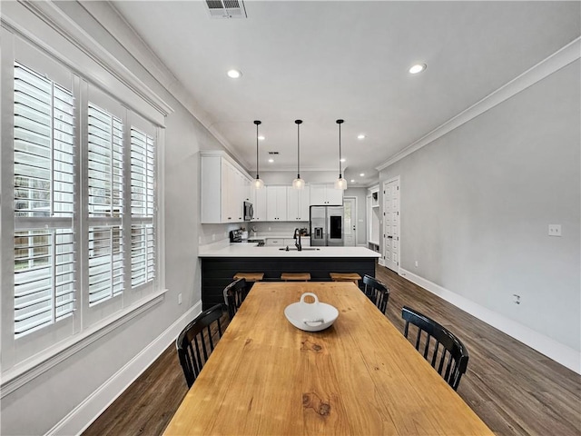 dining space featuring ornamental molding, sink, and wood-type flooring