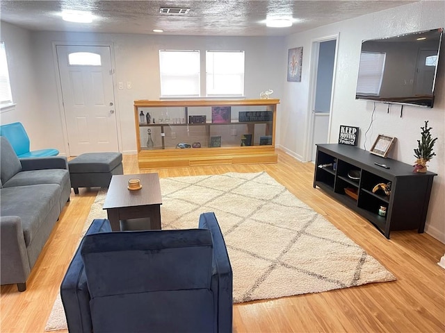 living room featuring visible vents, a textured ceiling, and wood finished floors