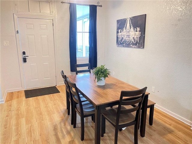 dining room with baseboards, light wood-style floors, and a textured wall