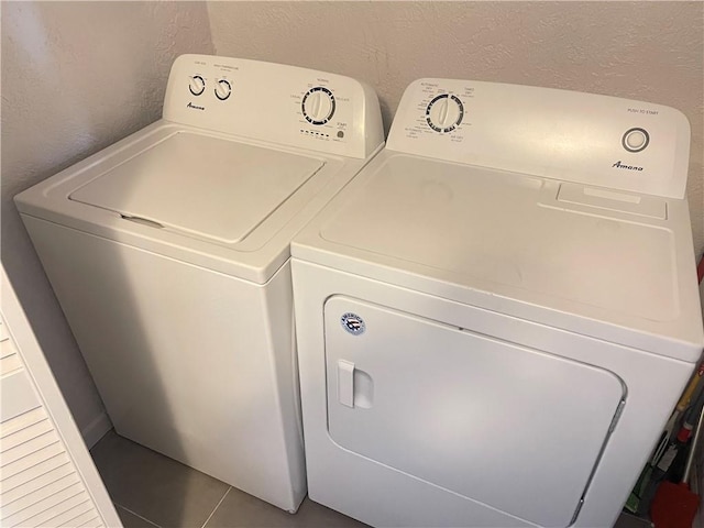 washroom with a textured wall, laundry area, and washing machine and clothes dryer