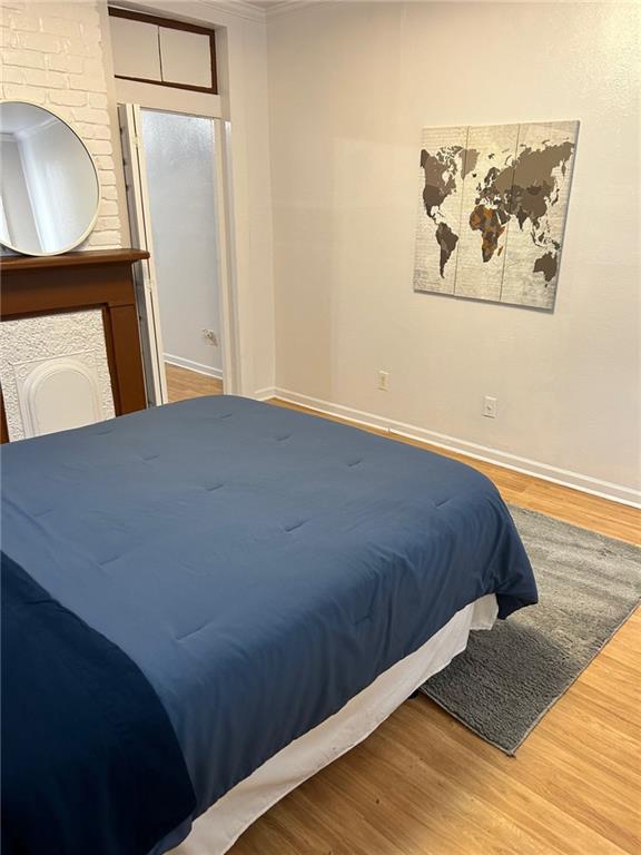 bedroom featuring wood finished floors, baseboards, and ornamental molding