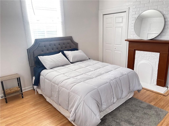 bedroom with wood finished floors, a closet, and baseboards