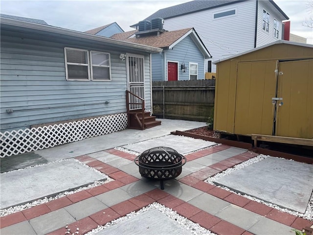 view of patio with entry steps, fence, a fire pit, a storage shed, and an outdoor structure