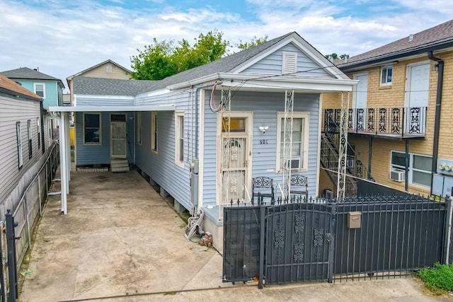 shotgun-style home featuring a gate, a fenced front yard, concrete driveway, and entry steps