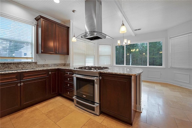 kitchen with light stone counters, visible vents, hanging light fixtures, stainless steel gas range, and island exhaust hood