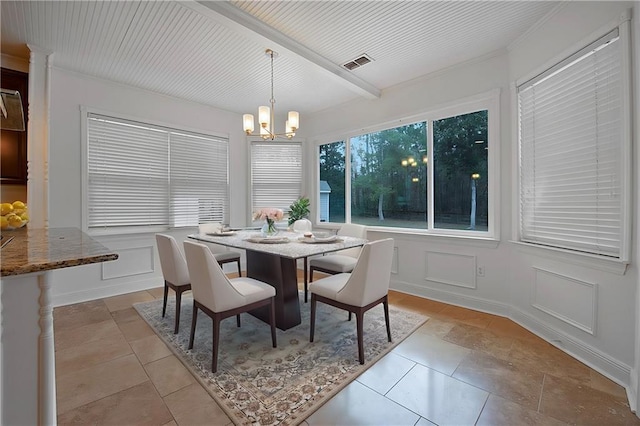 dining area featuring a chandelier, beam ceiling, visible vents, and a decorative wall