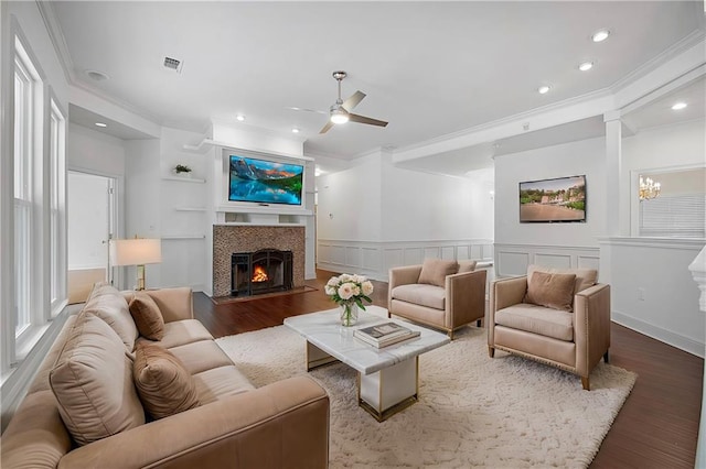 living area featuring crown molding, visible vents, a fireplace, and wood finished floors