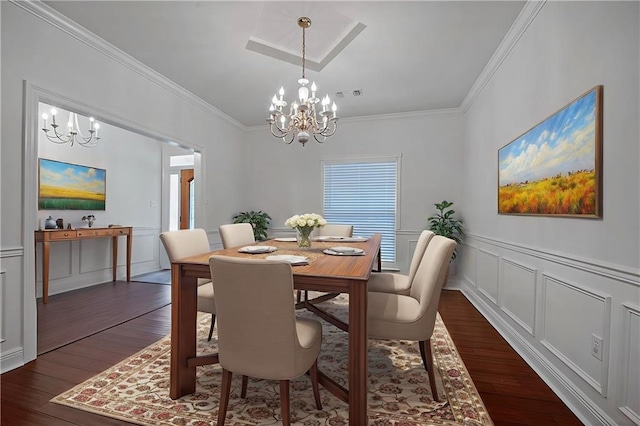 dining room with a decorative wall, a notable chandelier, visible vents, ornamental molding, and dark wood-style floors