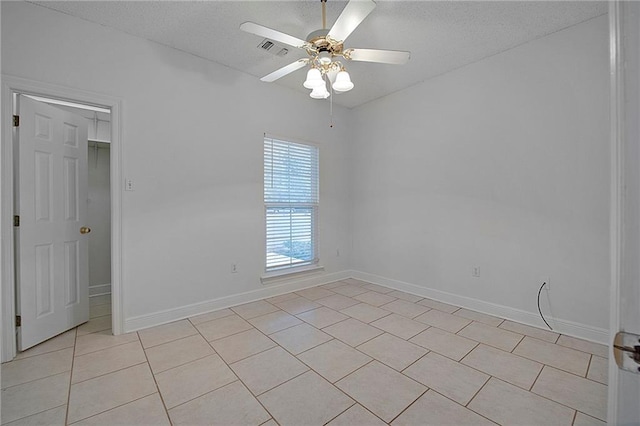 spare room with visible vents, light tile patterned flooring, ceiling fan, a textured ceiling, and baseboards