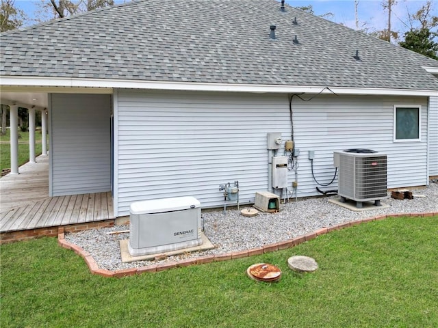 rear view of property featuring a shingled roof, a lawn, a wooden deck, and central AC unit