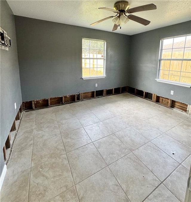 tiled empty room featuring a textured ceiling and ceiling fan