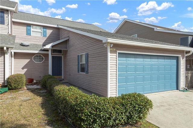 view of home's exterior featuring an attached garage, driveway, and a shingled roof