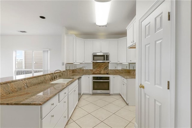 kitchen with light tile patterned floors, stainless steel appliances, a sink, visible vents, and light stone countertops