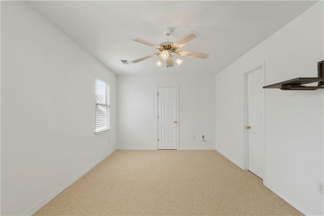 unfurnished room with light carpet, visible vents, baseboards, and a ceiling fan