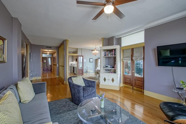 living room featuring hardwood / wood-style flooring and ceiling fan with notable chandelier