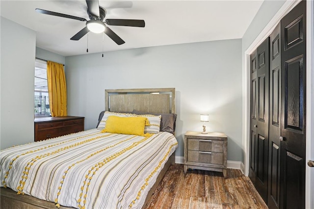 bedroom with dark wood-type flooring, ceiling fan, and a closet